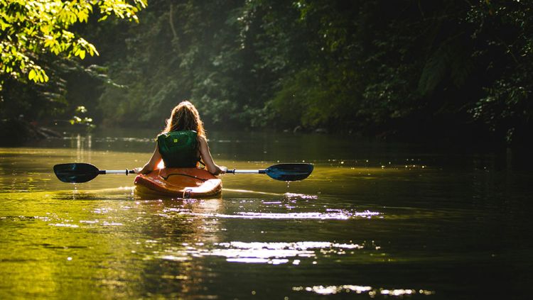 A woman kayaking along a river in Cunnamulla