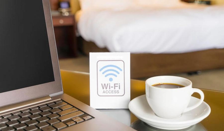 A cup of coffee next to a laptop and a free wi-fi sign inside a guest cabin
